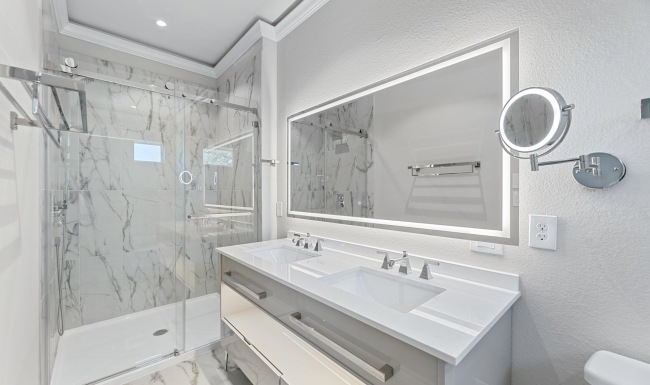 a bathroom with a shower, sink and mirror