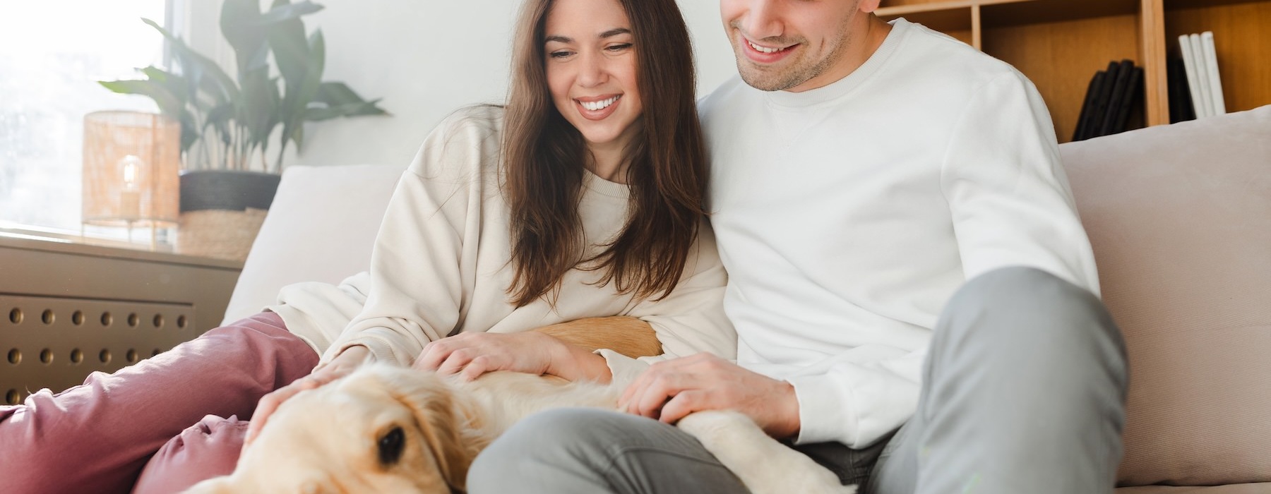 a man and woman sitting on a couch with a dog